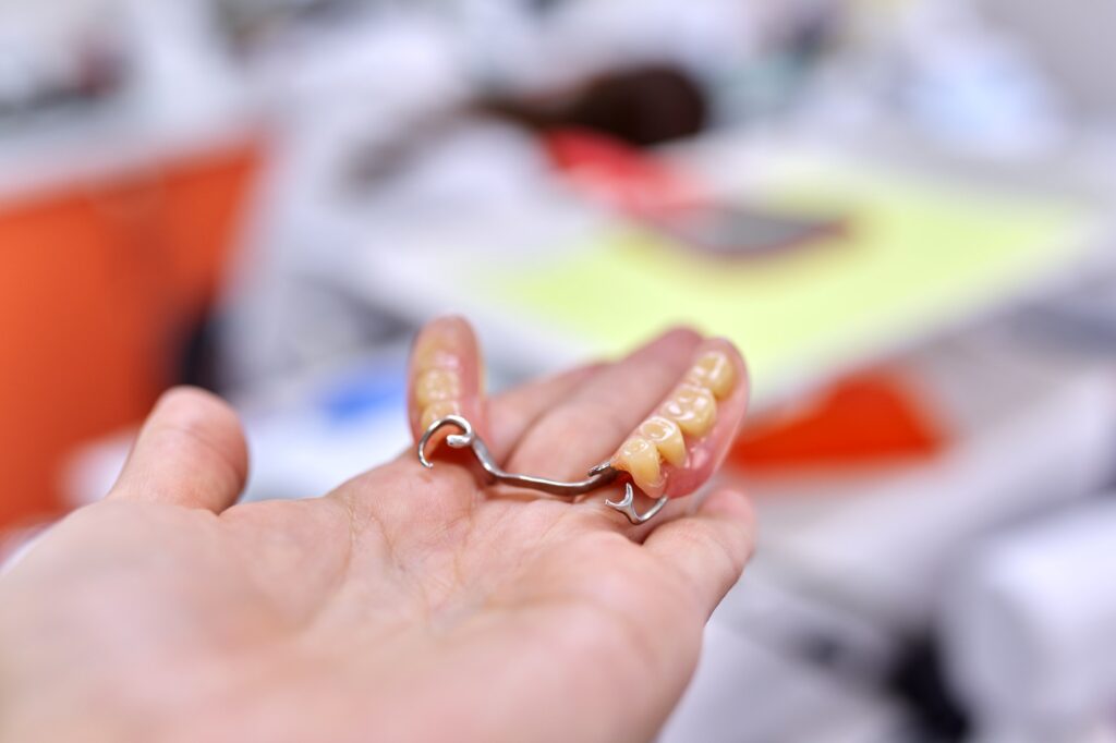 Dental implant model dental bridge in hand, dentist office background