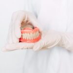 Dentist holding ceramic dental bridge. Front view of complete denture. Dentistry conceptual photo